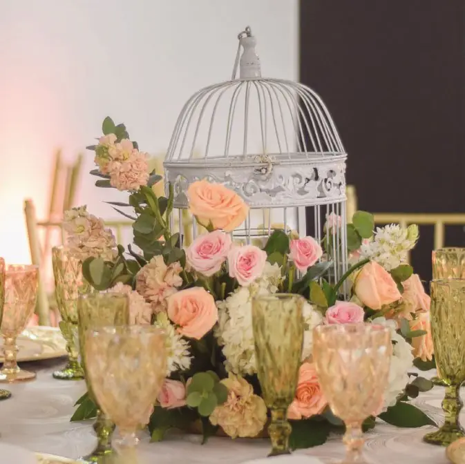 Centro de mesa con rosas durazno dentro de una jaula blanca