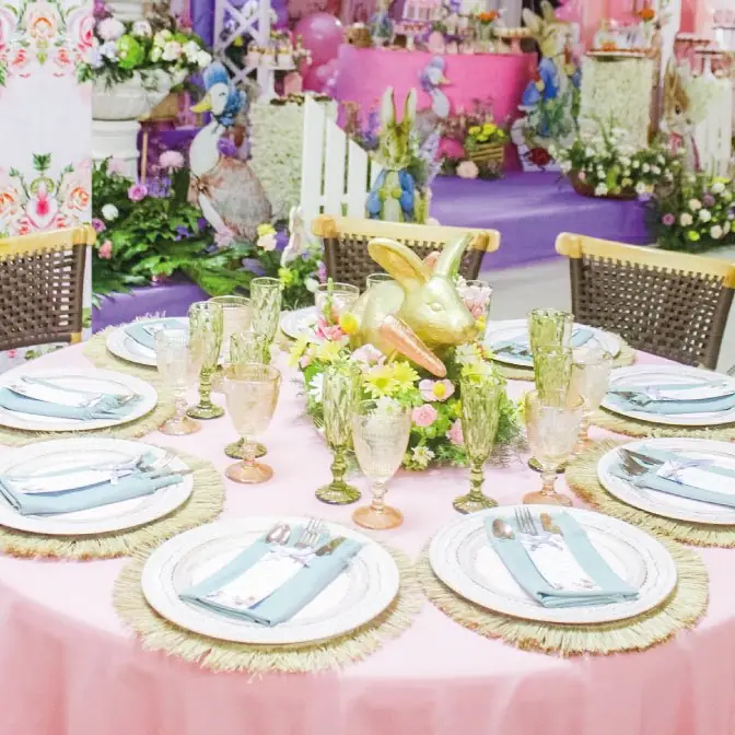 Mesa redonda con mantel rosado y flores en tonos pastel